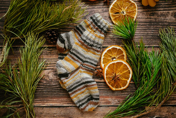 Colorful hand knitted kids socks and dried orange slices on dark wooden background