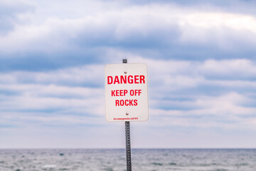 danger keep of the rocks for emergencies call 911 signage red letters on dirty white background...