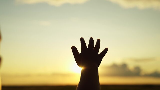 Little girl stretches his hand to sky, dreams in nature. Child is playing. Hand of child boy stretches to beautiful sky, sunset. Childrens dreams hopes, reach out your hands to sky. Childrens prayer