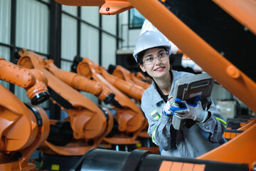 Caucasian female factory engineer using robot controller handheld panel for inspection industry robot arms with upgrade new programming software for automated technology in modern manufacturing.
