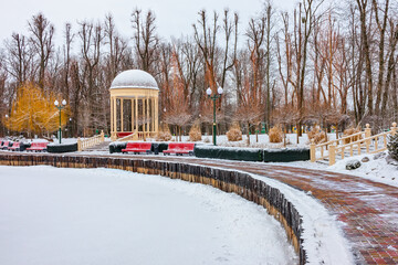 A beautiful city park with a gazebo near a frozen pond in Kharkiv city, Ukraine. Winter day after...
