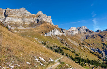 Mountain view in swiss alps with curvy hiking path near Engelberg, Switzerland. Beautiful blue sky in late summer.