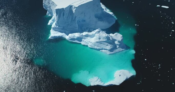 Huge iceberg floating in turquoise frozen ocean water. Antarctica majestic melting glacier landscape, polar scene background. Beauty wild untouched nature. Cinematic aerial top view rotation panorama