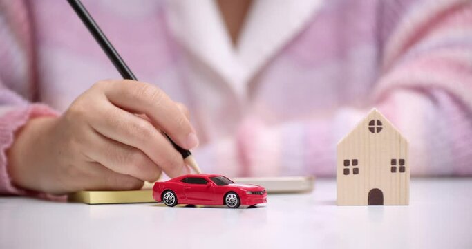 An individual planning and calculating the money needed for a new car and house on a loan.