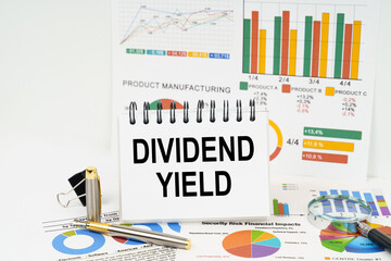 On the table are reports with graphs and a notepad with the inscription - Dividend yield