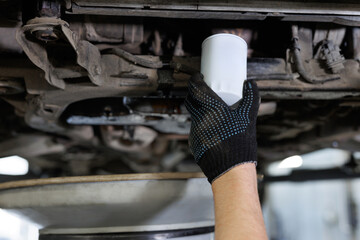 An auto mechanic changes the engine oil filter.