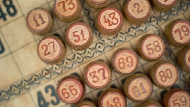 Cinematic close-up smooth rotating zoom in shot from above of Bingo wooden barrels in a row, woody figures, old numbers background, vintage board game, slow motion 120 fps commercial gimbal video