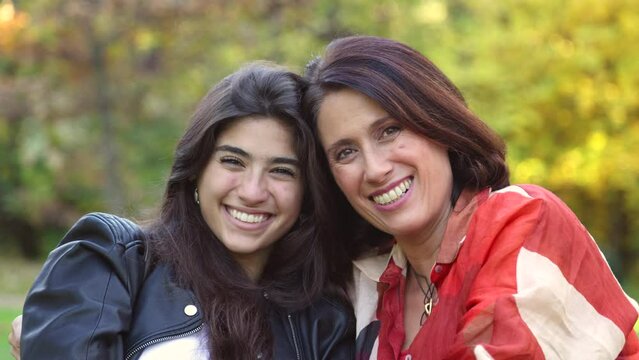 Mother and daughter laughing with heads together looking at camera