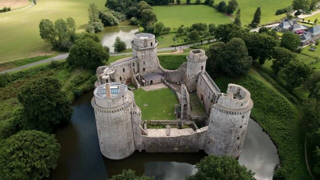 close drone shot around Hunaudaye Castle showing the different towers and its restoration on an overcast day during summer, Brittany, France