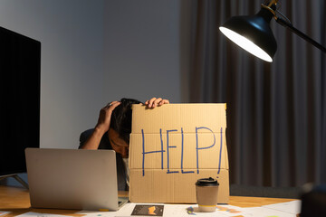 Frustrated and overworked businessman holding his head with a laptop computer and asking for help...