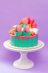 Birthday cake with turquoise frosting and pink birthday decorations ready for a birthday party, festive background. Pink donuts and macaroons