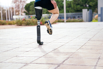 Obraz premium An athlete with a prosthetic leg is captured mid-stretch on a sunlit path, showcasing the fusion of human spirit and advanced technology.