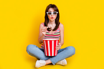 Obraz premium Full body photo of stunned girl wear knit tank in 3d glasses sit hold popcorn watch interesting movie isolated on yellow color background
