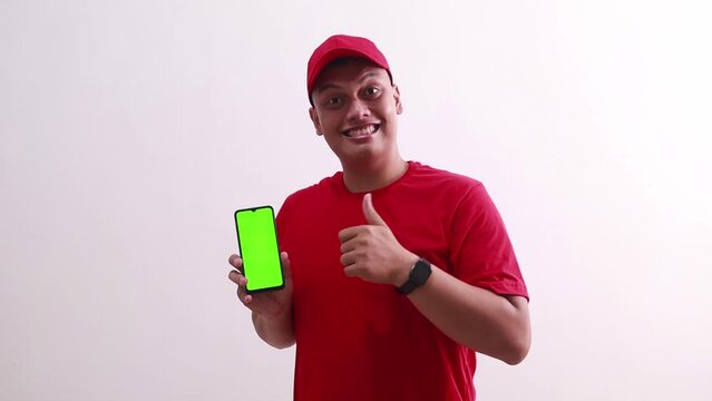 Wow amazed young asian deliveryman pointing green screen display cell phone