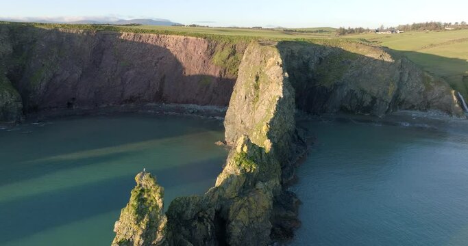 drone flying over sea cliff leading to two sheltered beaches at golden hour Copper Coast Waterford Ireland