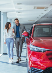 This car is exactly what we want. Beautiful young couple standing at the car dealership and making their decision.  Beautiful young couple standing at the dealership choosing the car to buy