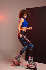 Sporty woman with curly hair in Kangoo jumpers on studio background - 718041306