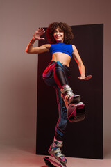 Beautiful sporty woman with curly hair in kangoo jumpers on studio background - 718041361