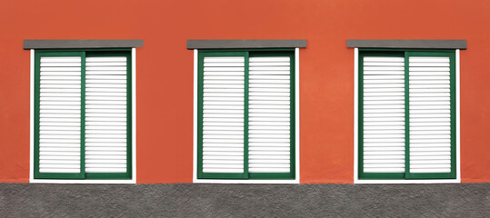 Three windows in a row. House closed shutters. Window shutters background. Red home wall facade....