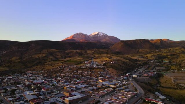 Drone shot flying over the small town of Putre in Chile at an altitude of 3650 meters with the Taapac&aacute; volcano in the background at sunset.