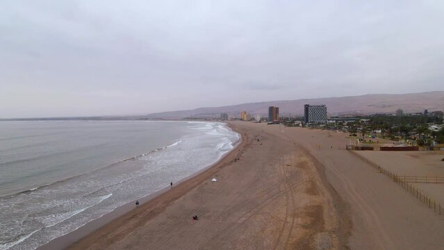 Drone shot flying along the beach in Arica, Chile on a cloudy day.