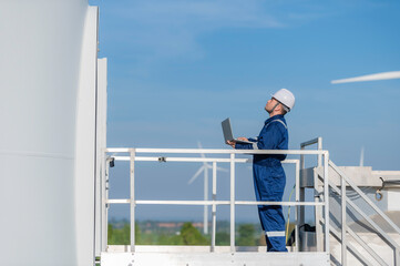 Two engineers working and holding the report at wind turbine farm Power Generator Station on mountain,Thailand people,Technician man and woman discuss about work