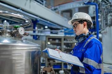 Asian engineer working at Operating hall,Thailand people wear helmet  work,He worked with diligence and patience,she checked the valve regulator at the hydrogen tank.