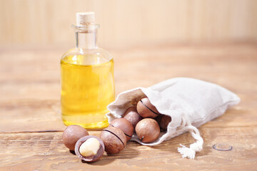 Macadamia Nuts in Jute Bag with Oil on Old Wooden Background