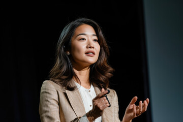 Portrait of a female speaker standing in front of the crowd presenting her presentation