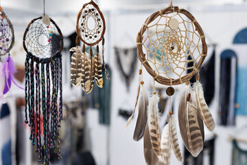 Various feather dream catchers made from the evil eye and souvenir magnets hanging on the walls and roof are sold in the market shop. - obrazy, fototapety, plakaty