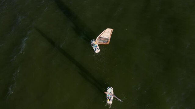 Woman and man control the sail of a windsurf board while sailing Aerial Top view