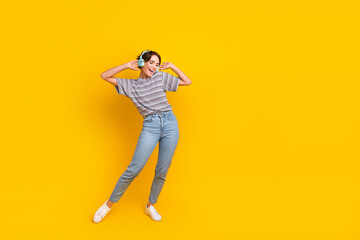 Fototapeta na wymiar Full body photo of overjoyed young lady arms touch headphones dance empty space ad isolated on yellow color background