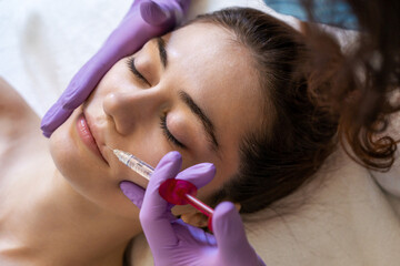 Caucasian lady getting lip filling injection at modern beauty salon, closeup. Female aesthetic cosmetology in a beauty salon.