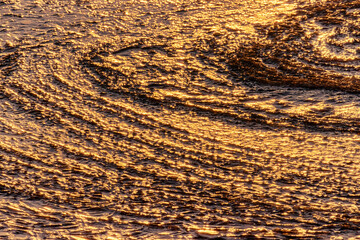 North-eastern European river after frosty winter. Ice began to melt, ice is saturated with meltwater. The morning sun colors ice surface, sunny path, iridescent reflection of sun on surface of ice