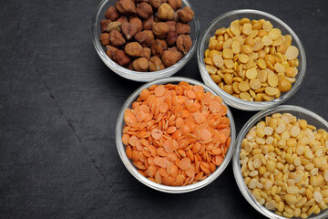 variety of lentils pulses red masoor mung dal yellow split chickpeas pigeon peas in mini glass bowl on black slate background