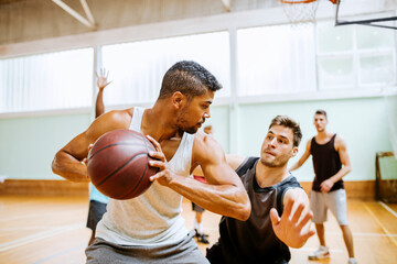 Young men playing basketball indoors