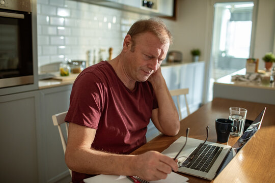 Middle aged man in pain working on laptop at home