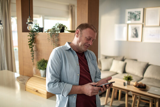 Middle aged man using smartphone at home