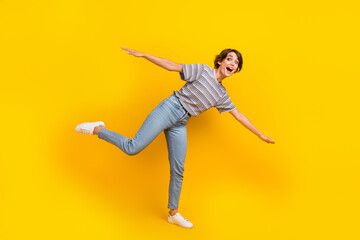 Fototapeta na wymiar Full body profile photo of cheerful lady stand one leg dance arms wings have good mood isolated on yellow color background