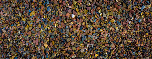 close-up of a gritty texture formed by a mixture of gravel and various stones.Smooth round pebbles texture background.
