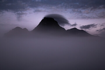 Top of mountain with clouds underneath during dawn
