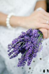 Woman in white dress with bouquet of lavender, closeup view