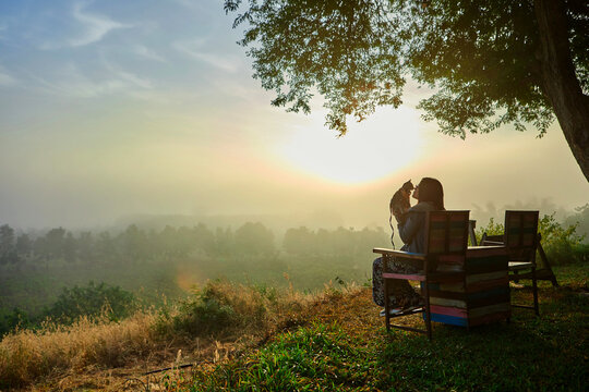 A woman kiss her cat during morning fog with sunrise
