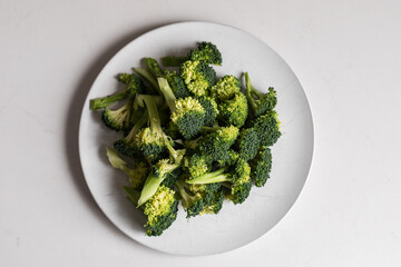 looking down on plate of fresh broccoli with white background