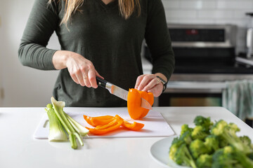 slicing an orange bell pepper for vegan dinner