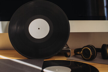 Vinyl record and headphones on desktop on computer background. Still life on a musical theme.