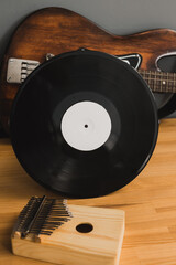 Musical still life, bass guitar, vinyl record and kalimba, on a wooden table.