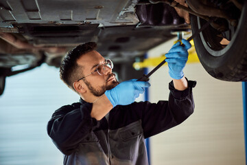 Side view of a focused mechanic, checking a tire, using some accessories, and looking underneath...