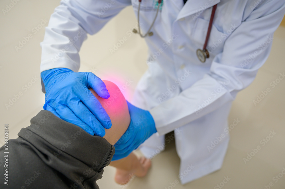 Wall mural a doctor in a white uniform is examining the knee of a woman who has a knee injury. knee treatment w