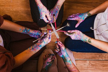 children gathered with hands stained with paint, community in a circle with hands full of paint,...
